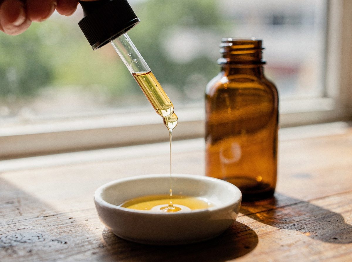 A dropper releasing a measured dose of oil into a small dish